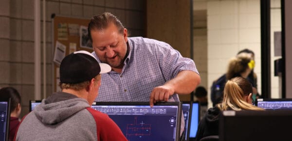 Teacher instructing student on computer