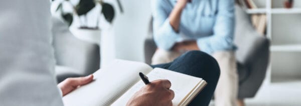 Psychologist speaking with patient and writing notes