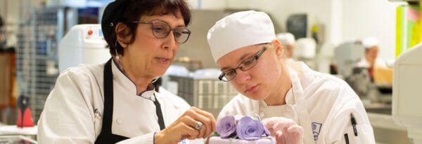 Instructor helping baking student with cake