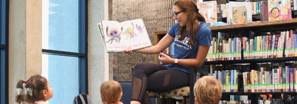 Woman reading a book to children in a library