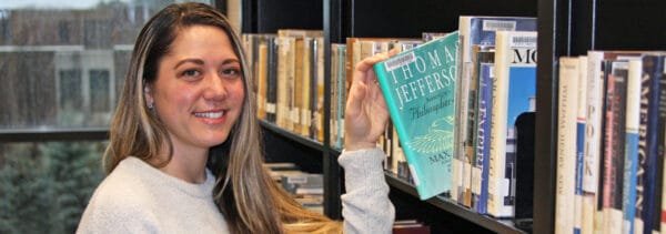 Student taking book off of a bookshelf in a library