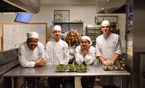 Culinary students at the Niagara Falls Culinary Institute gathered around table in lab