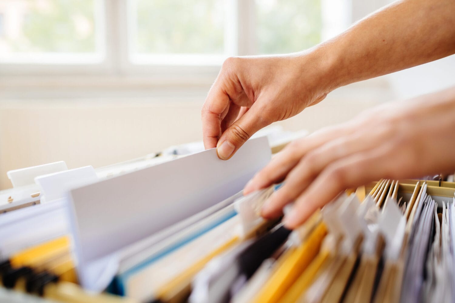 Hand going through file folders in cabinet