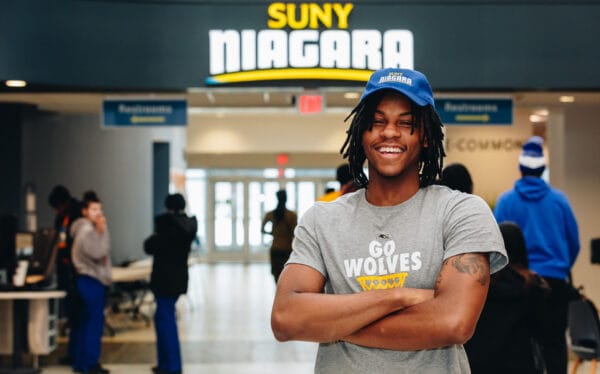 Student standing in front of SUNY Niagara sign in Learning Commons