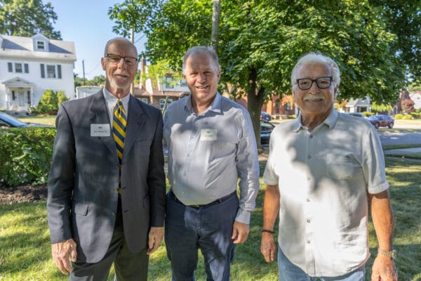 Three people smiling on a green, beautiful, sunny day at the 2025 Presidents Circle reception
