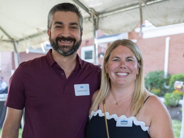 Two people under a white tent smiling at the 2025 Presidents Circle reception