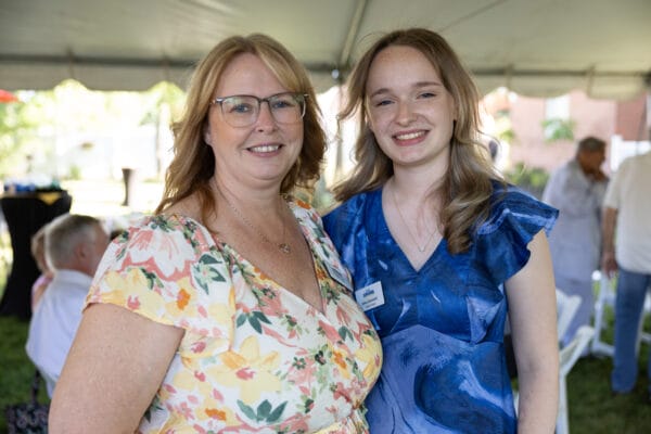 Two people under a white tent smiling at the 2025 Presidents Circle reception