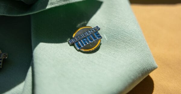 Presidents Circle pin on a light green folded cloth