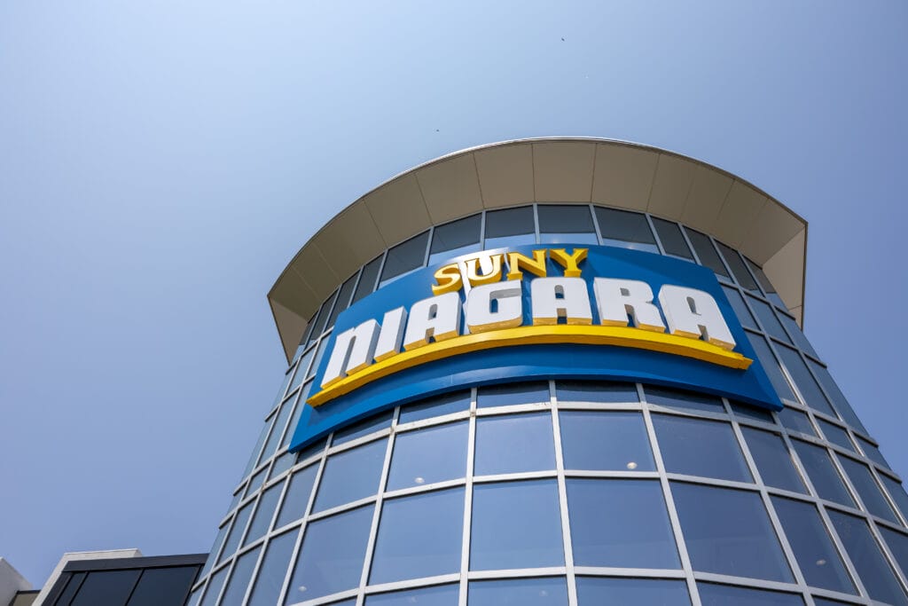 SUNY Niagara entrance with large, tall glass windows with a giant SUNY Niagara sign angled up in front of the sky