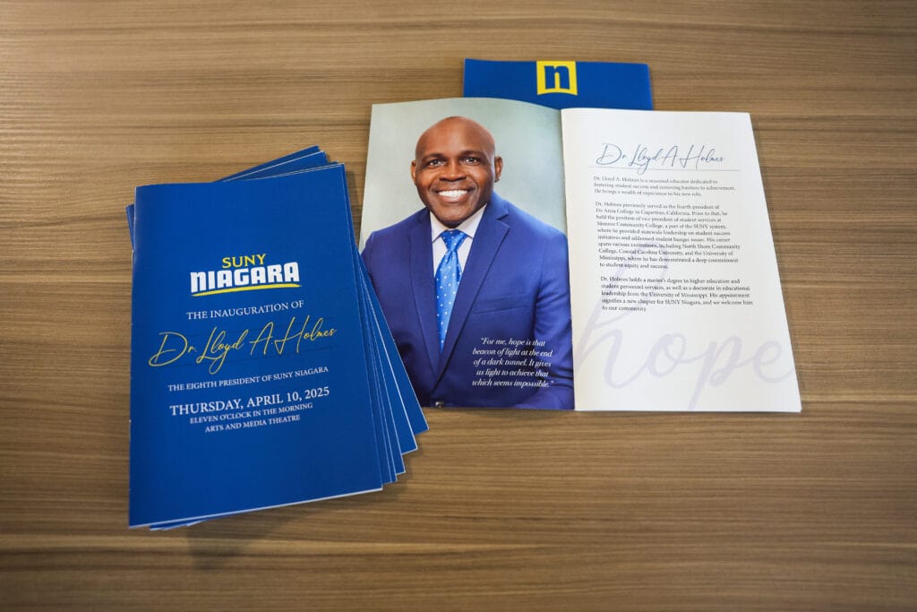 Photo of SUNY Niagara's Inauguration Invitation's on a desk with a picture of SUNY Niagara's president Dr. Holmes