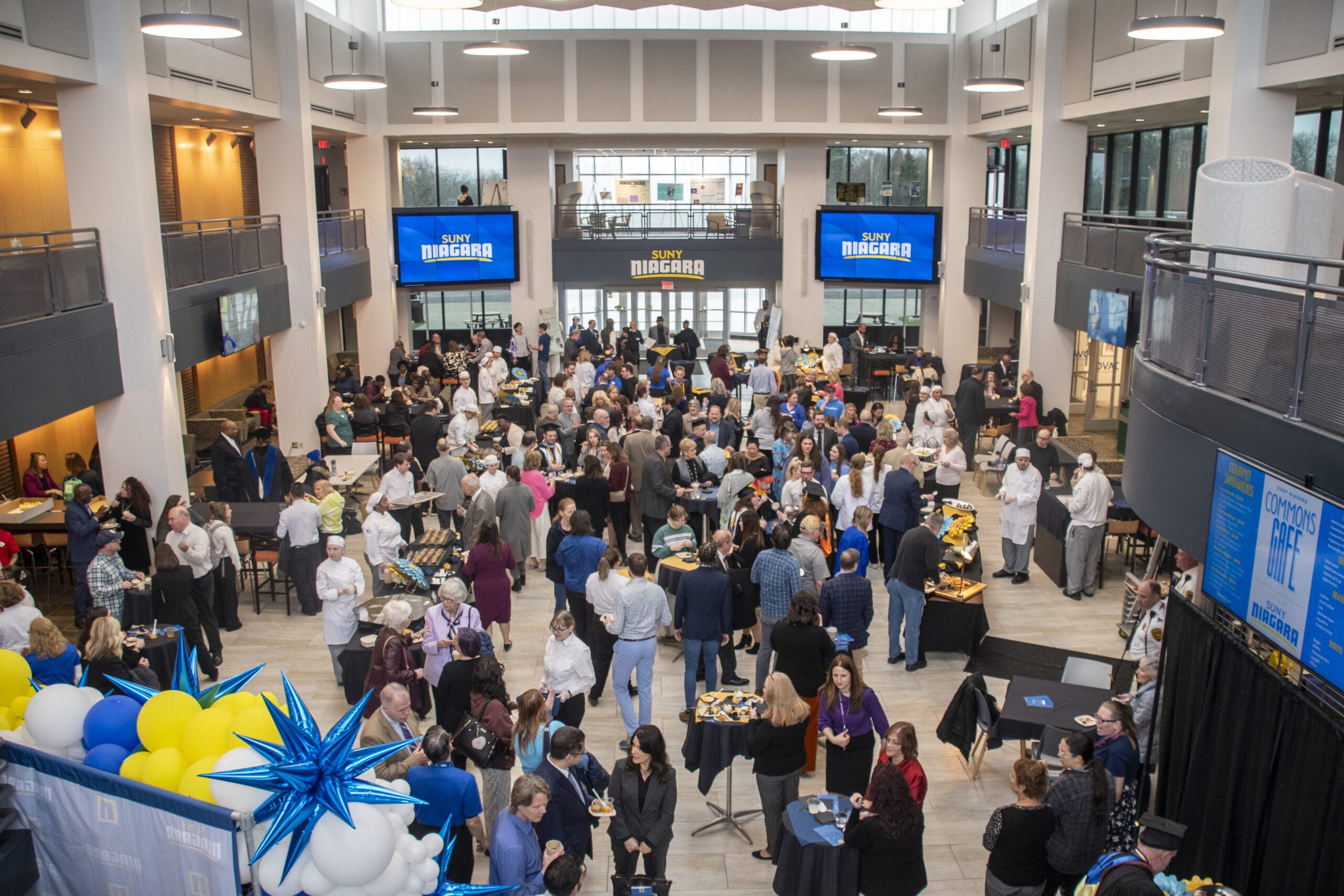 SUNY Niagara's Inauguration reception with hundreds of people in a large room with balloons and food