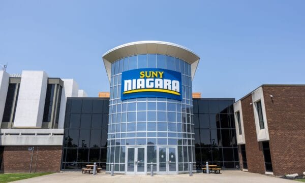 SUNY Niagara entrance with large, tall glass windows with a giant SUNY Niagara sign angled up in front of the sky