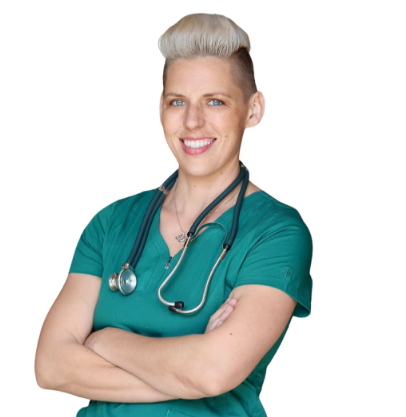 A smiling person with short, styled blonde hair wears green scrubs and a stethoscope around their neck, standing with arms crossed against a white background.
