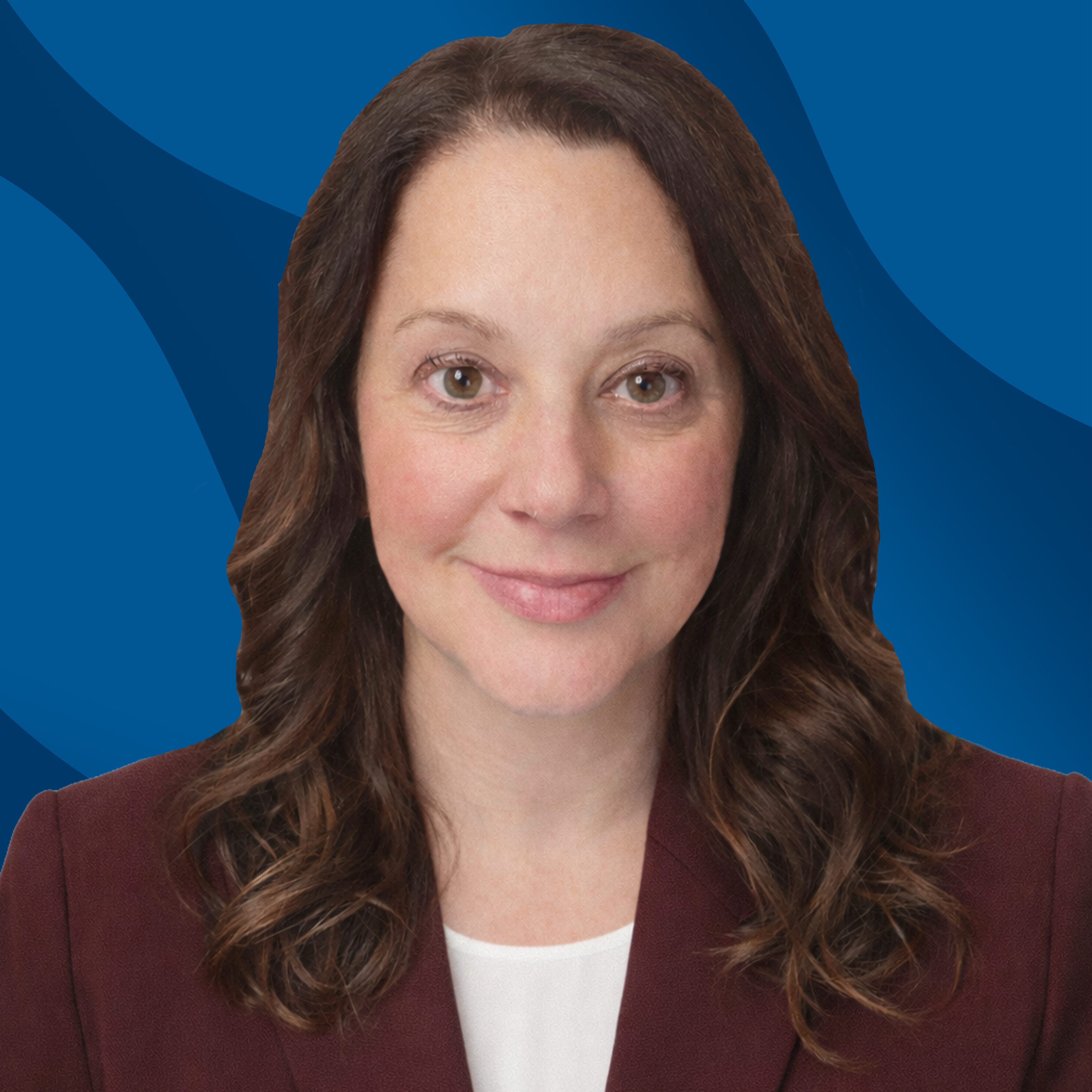 A woman with long brown hair wearing a maroon blazer and white top, smiling, posing in front of a blue abstract background.