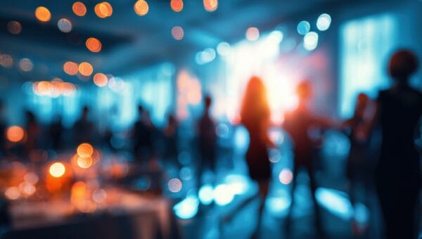 A blurred image of people dancing and mingling at an indoor event or party, with warm lights and colorful bokeh creating a festive and lively atmosphere.