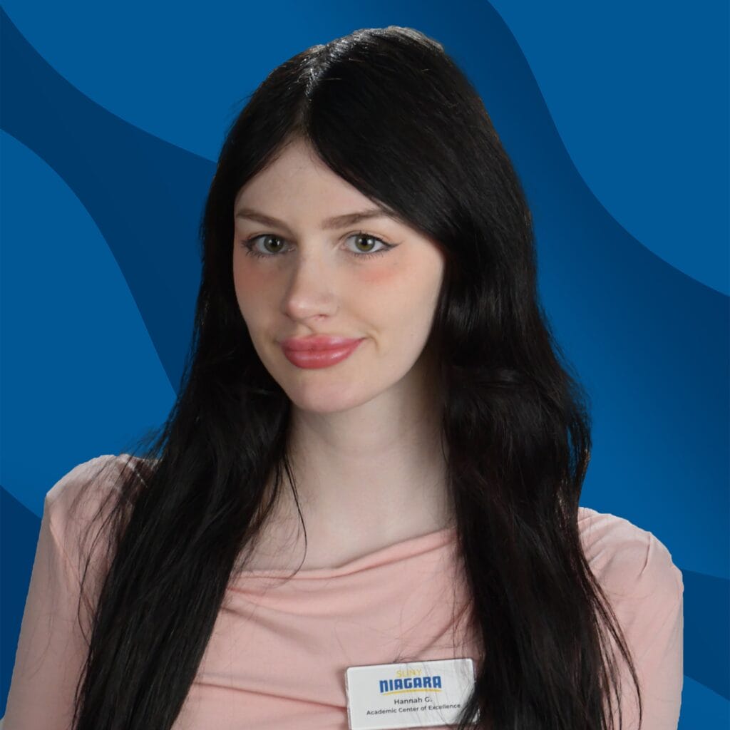 A woman with long dark hair wearing a light pink top and a Niagara College name tag stands in front of a blue wavy background, smiling slightly at the camera.
