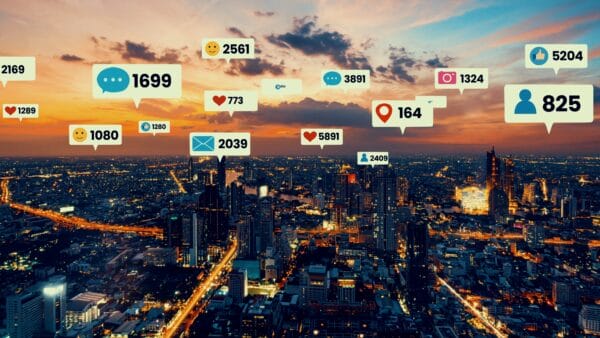 A city skyline at sunset with social media notification icons, such as likes, messages, and location pins, floating above buildings, representing digital connectivity.