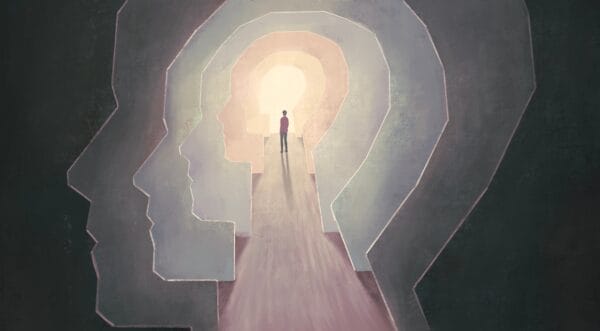 A person stands on a path leading through multiple translucent human head silhouettes, symbolizing self-discovery or introspection, with light shining at the end of the path.