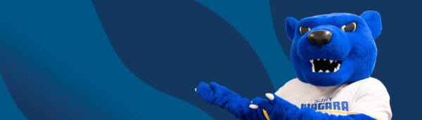 A blue panther mascot wearing a SUNY Niagara shirt stands against a blue abstract background, gesturing with both paws.