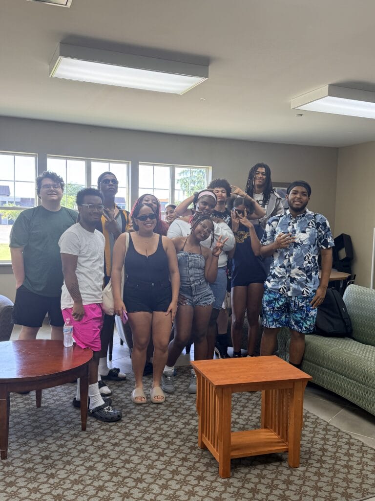 A group of twelve young adults posing for a photo together in a lounge area.