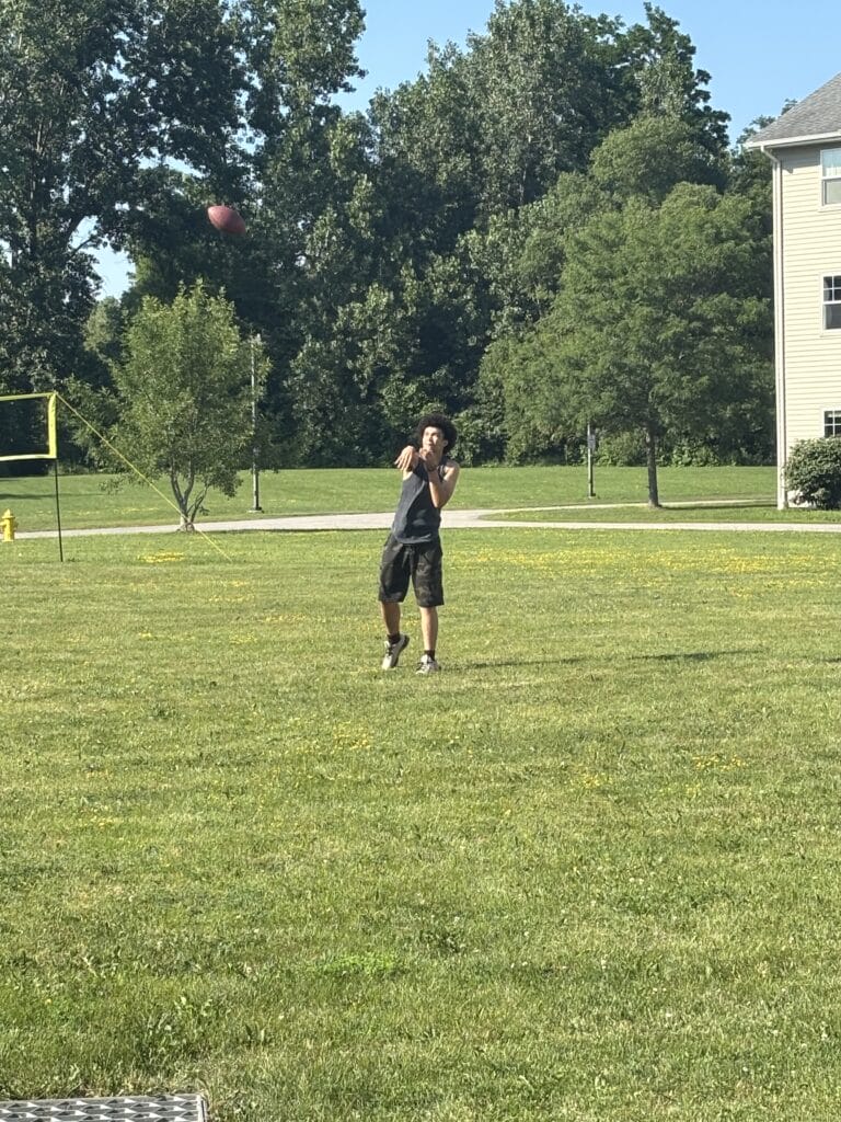 A young man throwing a football in a grassy park.