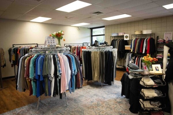Clothing racks and tables filled with folded and hanging garments in a retail store.